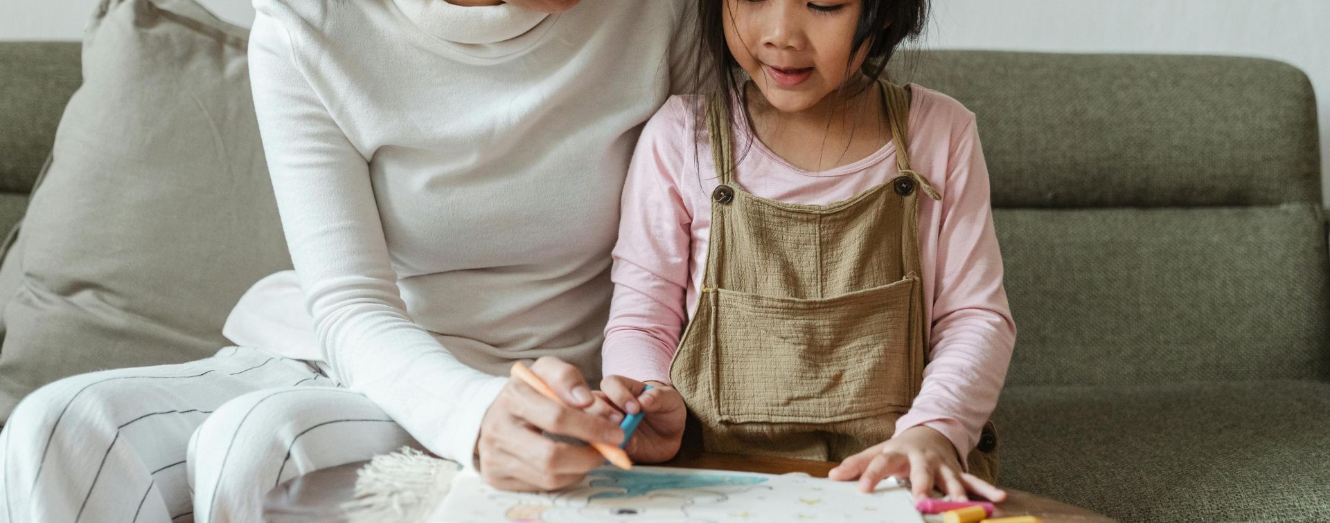 Smiling woman tutoring ethnic girl at home