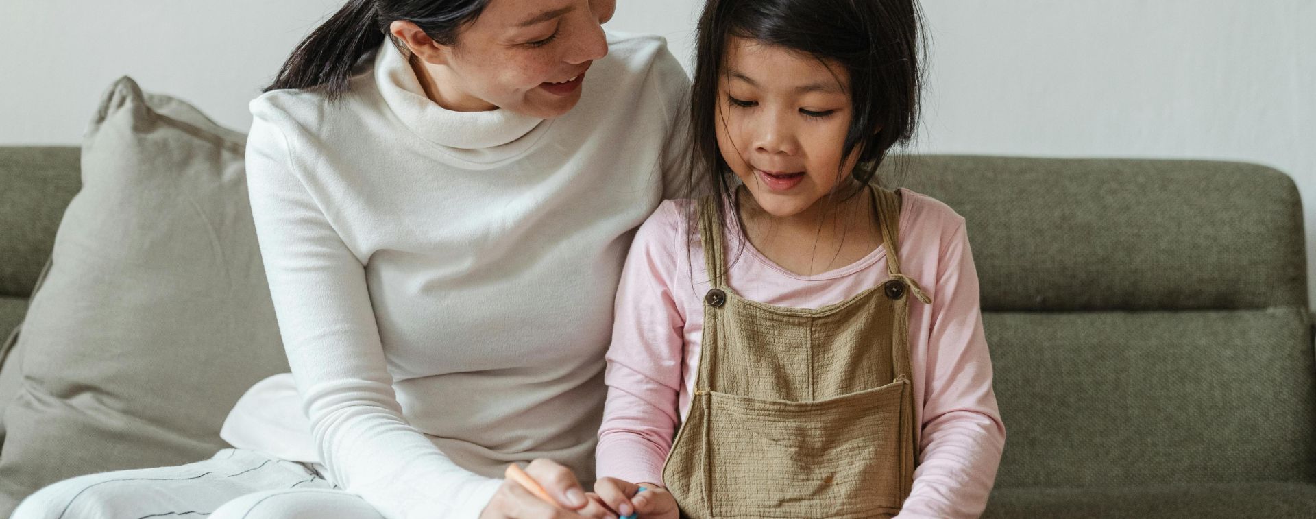 Smiling woman tutoring ethnic girl at home