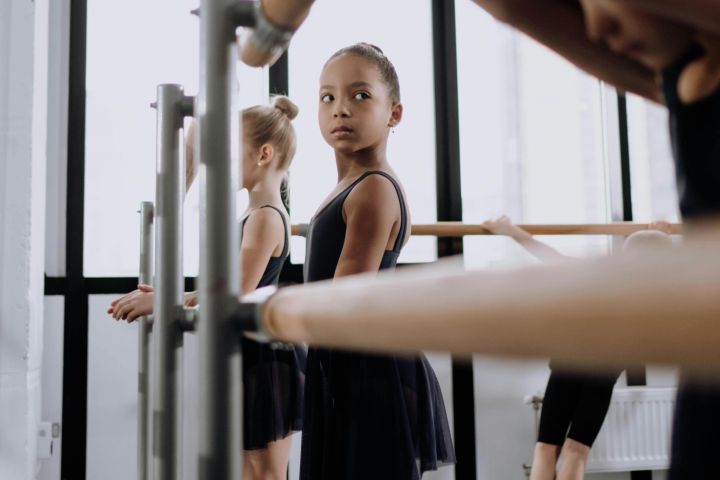 Children practicing ballet at the barre in a dance studio.