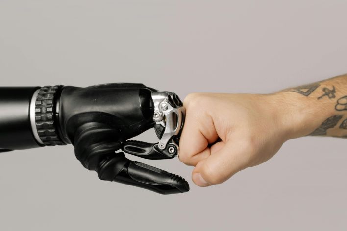 Close-up of a human fist bumping a prosthetic hand, symbolizing technology and human connection.