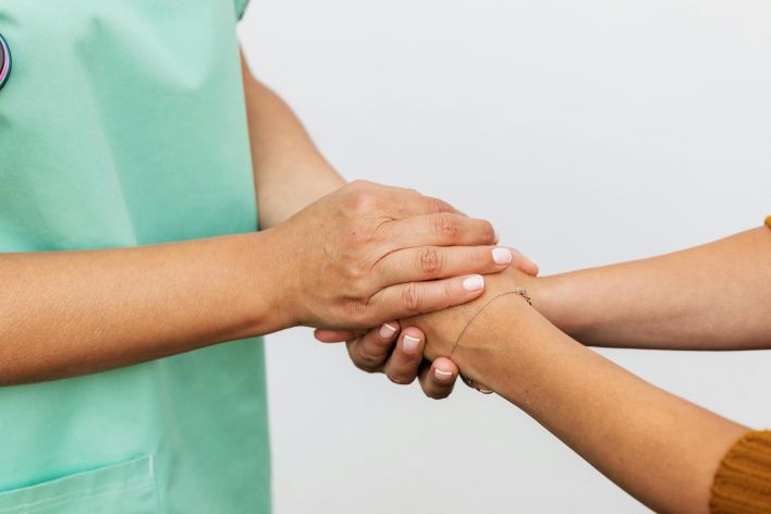 Close-up of two hands showing a supportive gesture, emphasizing care and compassion.