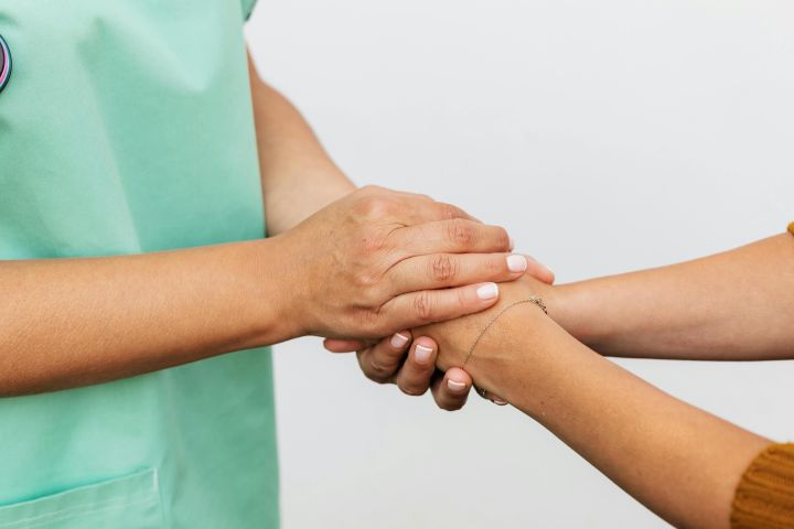 Close-up of two hands showing a supportive gesture, emphasizing care and compassion.